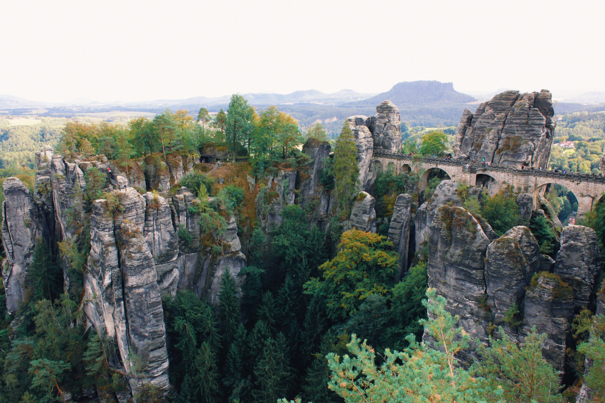 Vista de uma das trilhas do parque e a Ponte Bastei, na direita da foto, construída no meio das pedras em 1851.