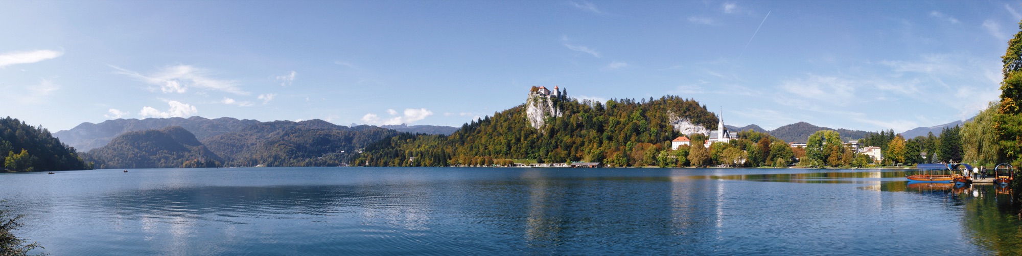 Uma das vistas do lago Bled: castelo de Bled ao meio (construído por volta do ano de 1011 sobre um penhasco na margem do lago) e igreja de St. Martin à direita.